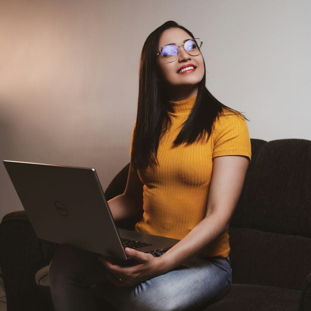 Lachende vrouw met een laptop op schoot op de bank